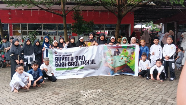 Para murid SD Negeri Borong Makassar bersama guru dan orang tua berpose sambil membentangkan spanduk kegiatan Bukber dan Bagi Takjil, sebelum turun membagikan takjil kepada pengendara dan warga yang melintas di Jalan Borong Raya saat Ramadan.